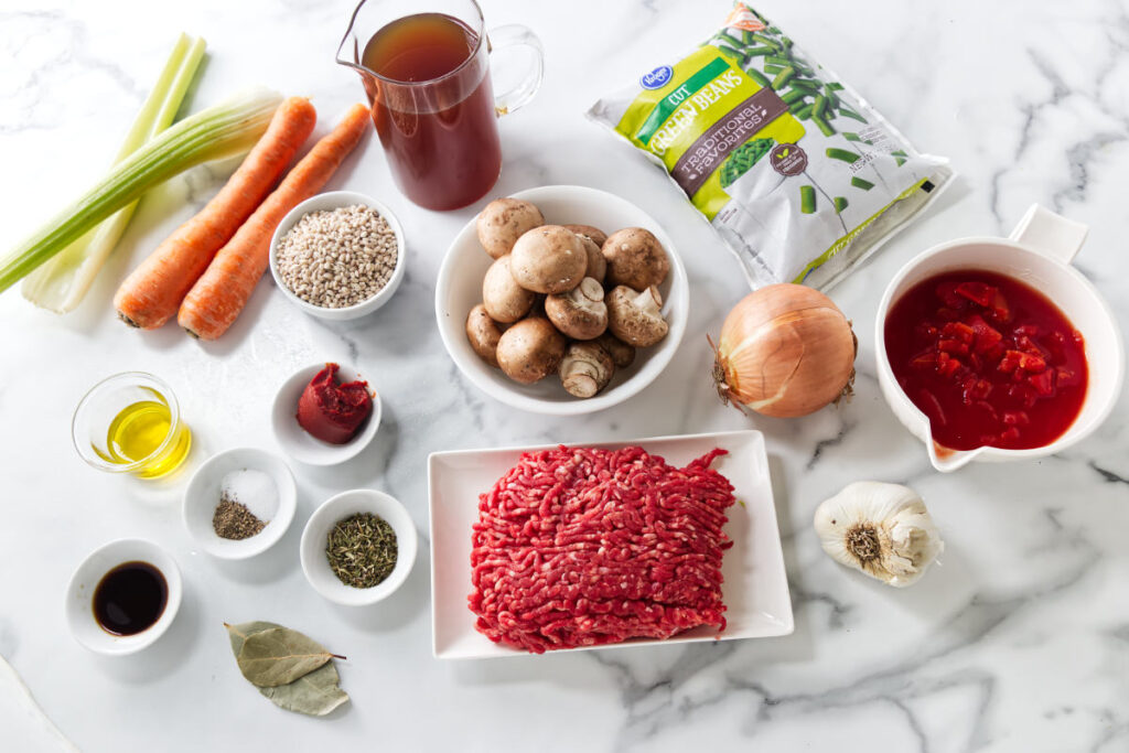 Soup ingredients including ground meat, vegetables, mushrooms, broth, and seasonings.