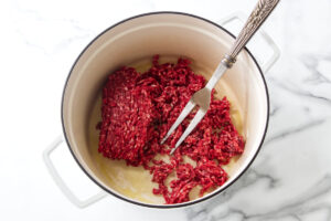 Ground meat cooking in a pot with a fork.
