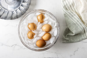 Hard-boiled eggs cooling in a glass bowl of ice water.